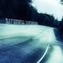 RAY RUSSELL / DANGEROUS BENDS. Eine leere Straße führt durch einen Wald., CD