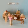 ADHD 10. Holzfiguren als Band mit Trompete, Klavier, Schlagzeug und Gitarre. Farbe und Form betonen Musikszenario.
