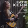 "Katie Kern, Blues for the Highway." Eine Frau spielt Gitarre vor einem Holzzaun mit Blüten im Hintergrund. Logo: Wolf Records., CD