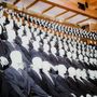 Grüne "EXIT"-Schilder an Türrahmen; viele menschenähnliche Figuren in Anzügen ohne Gesicht in einem Hörsaal., LP