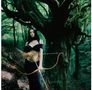 Ich kann den Text nicht identifizieren. Eine Frau mit Pfeil und Bogen in einem grünen Wald, getragenes Kleid schwarz., CD