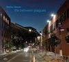 Text: “Stefan Bauer” und “life between plagues”. Abendliche Straßenszene mit beleuchteten Gebäuden und Bäumen., CD