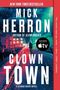 Texte: Mick Herron, Clown Town, A Novel, Author of Slow Horses. Eine Person geht in einer neonbeleuchteten, regnerischen Gasse.