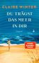 Titel: „DU TRÄGST DAS MEER IN DIR“. Eine Frau läuft am Strand entlang; im Hintergrund das Meer und ein kleines Segelboot., Buch