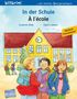 Text: "In der Schule / À l'école", "Deutsch Französisch". Illustration von drei fröhlichen Kindern vor einer gelben Schule.