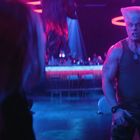 Verpixelte Bar mit runden, leuchtenden Ringen, neonfarbenes Licht, muskulöser Mann in Tarnhose schreit.