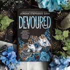 „Devoured“ von Jordan Stephanie Gray. Ein Zitat lobt das Buch. Schmuckkrone mit blauen Edelsteinen und Blumen.