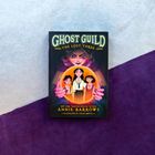 Auf einem Buchcover steht: "GHOST GUILD THE LOST THREE". Es zeigt drei Kinder in einer Kristallkugel, die von einer mystischen Figur gehalten wird.