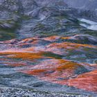 Peter Kubelka, alle Fotografien von. Eine Landschaft mit farbigen, moosbedeckten Hügeln in orange und grün.
