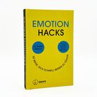 "EMOTION HACKS" in blauen und schwarzen Buchstaben auf gelbem Hintergrund; darunter ein Smiley mit Text: "50 Wege, sich schnell besser zu fühlen."