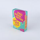 Auf einer türkisfarbenen Schachtel steht: "Zwei Wahrheiten und eine Lüge". Sprechblasen-Design.