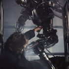 Ein Roboter in dunkler Umgebung greift nach einer liegenden Person auf einer Treppe.