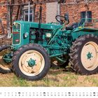 "DEZEMBER", Kalender mit Datum. Alter grüner Traktor vor gemauerter Wand auf einem Hof.