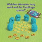 Text: "Welches Monster mag wohl welche Lieblingsspeise?"  
Fünf blaue Monsterfiguren stehen um gelbe Plättchen und Münzen. Oben rechts liegt ein Monster in einer Hängematte.