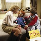 „Good Guys“ steht auf einer gelben Box. Eine Frau, ein Kind und eine rothaarige Puppe sitzen auf einem Sofa.