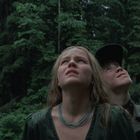 Ich kann keine Texte oder Logos im Bild erkennen. Zwei Menschen schauen in einem Wald gespannt nach oben.