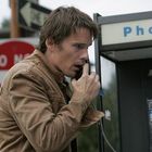 „Phone“ auf Telefonzelle. Ein Mann in brauner Jacke telefoniert aufgebracht mit einem öffentlichen Telefon.