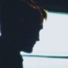 Eine dunkle Silhouette einer Person vor einem hellen Fenster, das den Hintergrund beleuchtet.