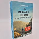 Buchtitel: "The Impossible Journey". Untertitel: "10 Jahre · 203 Länder · Null Flugzeuge". Mann vor bewaldetem Hügel.