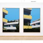 Erdgeschoss Raum 7. Zwei moderne Gemälde an einer weißen Wand zeigen Gebäude mit gelben Balkonen, vor blauem Himmel.