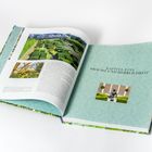 Kapitel Eins: Pracht und Herrlichkeit. Geöffnetes Buch mit Bildern von Gärten auf pastellgrünen Seiten.