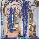 "Sammlungsintervention, Museum Nikolaikirche, Foto: Volkmar Otto" Vor einer gotischen Innenarchitektur hängen blaue Dekorationen.
