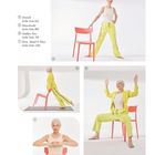 Dreieck, Heuschrecke, Goddess Pose, Herz, Hand & Hirn. Eine ältere Frau in gelber Kleidung macht Yoga zusammen mit einem Stuhl.