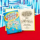 Auf dem Cover steht "SCUBA CATS". Zwei fröhliche, tauchende Katzen in Tauchanzügen. Farbenfrohe, verspielte Illustration.
