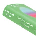 Grünes Buchcover mit dem Text "ADRIANO SACK IN DIE SONNE FLIEGEN". Farbakzent mit Blau und Rot verwischt.