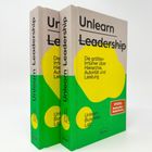Zwei Bücher mit dem Titel "Unlearn Leadership" und großem gelben Kreis auf grünem Hintergrund.