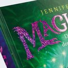 Glitzernde Buchstaben "MAG", grüner Hintergrund, leuchtend und fantasievoll. Oben steht "JENNIFER".