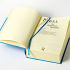 "BIBEL in gerechter Sprache" steht auf der Titelseite eines geöffneten Buches mit blauem Einband und Lesezeichen.