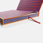 Ein Buch mit blau-orangem geometrischem Muster. Ein rotes Lesezeichen ragt heraus.