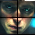 Ein Gesicht ist in Quadrate unterteilt. Ausdrucksvolle Augen, ernste Mimik. Rechts bunte Unschärfe, links ein Glas.