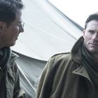 Zwei Männer in Winterkleidung stehen im Gespräch. Der eine trägt eine Brille, der andere schaut ernst. Im Hintergrund ein Zelt.