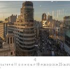 "Gran Via" steht unten geschrieben. Stadtbild bei Sonnenuntergang mit belebter Straße und Hochhäusern.