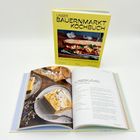 Buchcover mit "UNSER BAUERNMARKT KOCHBUCH". Geöffnetes Buch zeigt Rezept: "KÜRBISKUCHEN MIT TOPFENCREME".