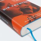 Buch "Die Tochter" mit rotem Cover, blaue Schrift, blaues Lesebändchen.Gesicht einer Frau auf dem Umschlag.