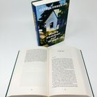 Der Titel auf dem Buchdeckel ist "Wolfssommer auf Wigø" von Catrin Ormestad. Ein Buch ist aufgeschlagen, der Leseabschnitt heißt "Große Taten". Im Hintergrund steht das Buch mit einem Gemälde auf dem Cover, das ein einfaches Haus zeigt.