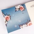 Keine Texte sichtbar. Ein blauer Hintergrund mit Blumen und Schneeflocken-Illustrationen. Rechts ein aufgeschlagenes Buch.