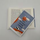 Auf einem Buch liegt ein Roman: "Anne Akrich, Kylian und das Buch meines Lebens". Cover in Blau mit Wolken.
