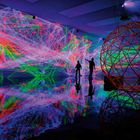 Texte: "INSTALLATIE, Complex Meshes, sinds 2015." 
Lichtinstallation mit bunten Laserfäden und Reflektionen im Raum.