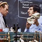 Der Text "Tomorrow: Read 8, 10-25. Next exam!" erscheint auf einer Tafel. Zwei Männer, einer hält einen Schädel.