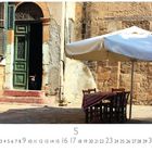 Kalenderseite mit Aufschrift: "Caféhaus Nikosia 5." 
Zu sehen: Alte Tür, Hund auf Stufen, Tisch mit Sonnenschirm.