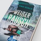„Weißer Rausch“ von Anu Ojala, ein Thriller. Cover zeigt schneebedeckte Hütte am gefrorenen See unter grünen Nordlichtern.