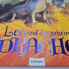 „Leo und der geheime Drache“ in blauer und schwarzer Schrift auf feurigem Hintergrund mit Drache. Unten „esslinger“.