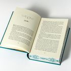 Seite zeigt Kapitel "Apollo". Buch in Hardcover mit dekoriertem Rand und floralem Muster in der Mitte geöffnet.