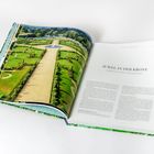 Text: "JUWEL IN DER KRONE, HAMPTON COURT, EAST MOLESEY." Aufgeschlagenes Buch zeigt eine Luftaufnahme eines prachtvollen Gartens.