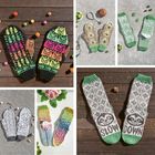 Texte: "SLOW DOWN". Verschiedene handgestrickte Fäustlinge und Socken mit bunten Mustern auf Holz- und Steinuntergrund.