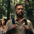 Es gibt keinen Text. Ein Mann mit Rucksack und Bart läuft durch einen grünen Wald, eine Frau folgt ihm.
